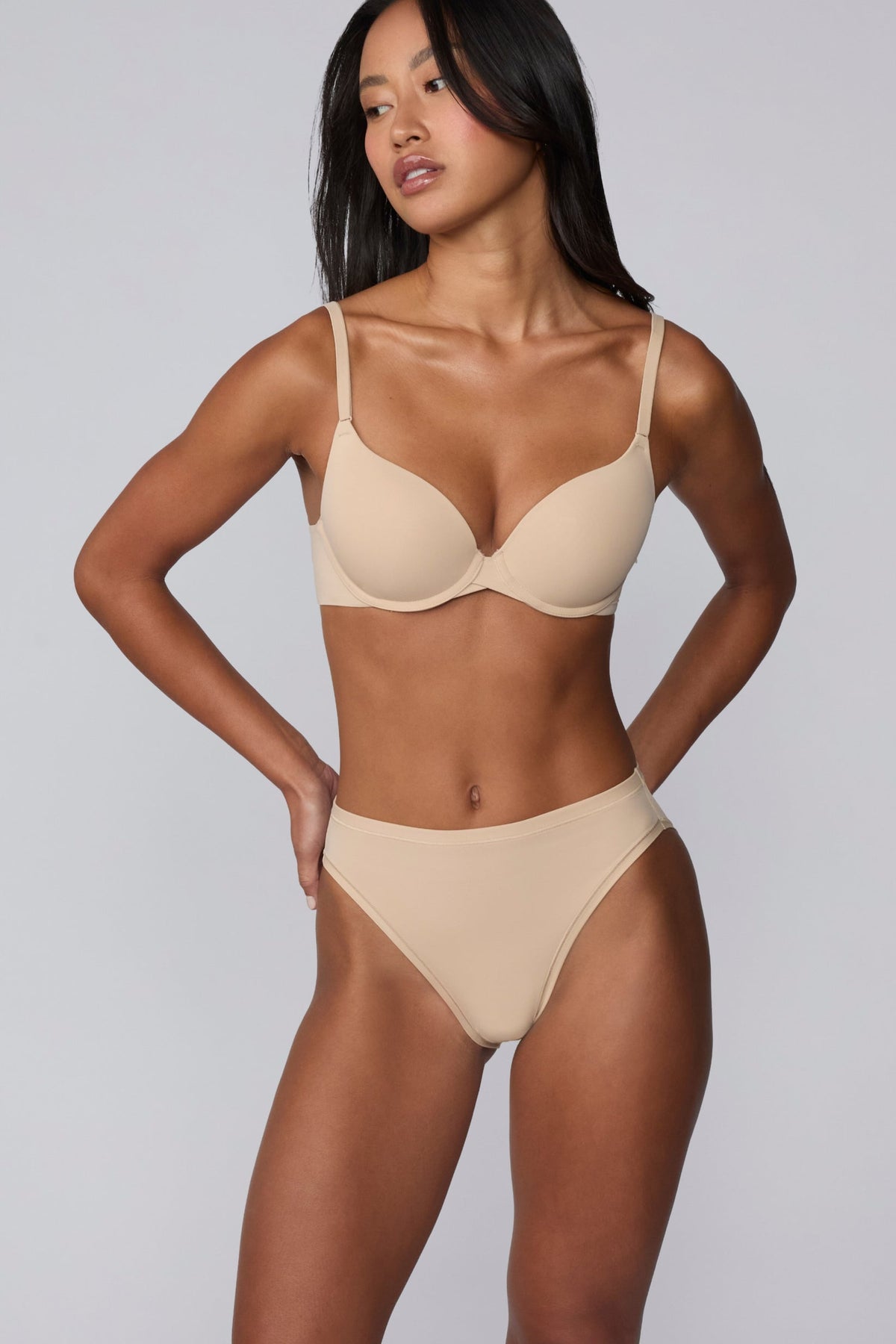 On a light gray studio backdrop, Amber wears the Bliss French Cut Brief in Beige, shown from the front to highlight the mid-rise waist, full front coverage, and smooth, no-show fabric.