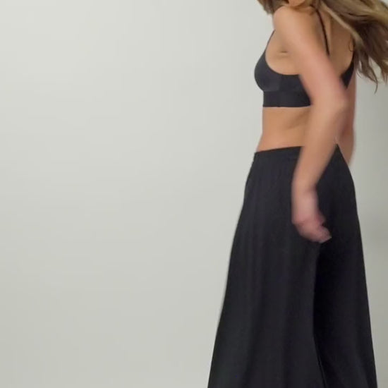 Video of a model turning against a white backdrop wearing the Bliss Triangle Bralette and Sunday Pima Palazzo Pant in Black.