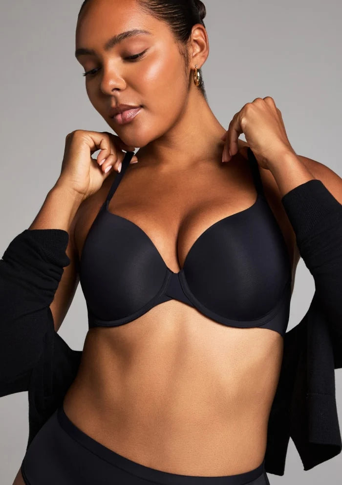 Model in a black molded-cup bra styled with a black jacket, hands at the collar.